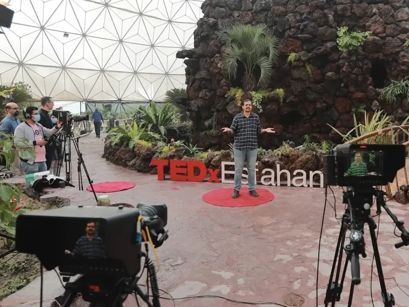 Iman Ebrahimi speaking on the TEDxEsfahan stage during a recorded talk.